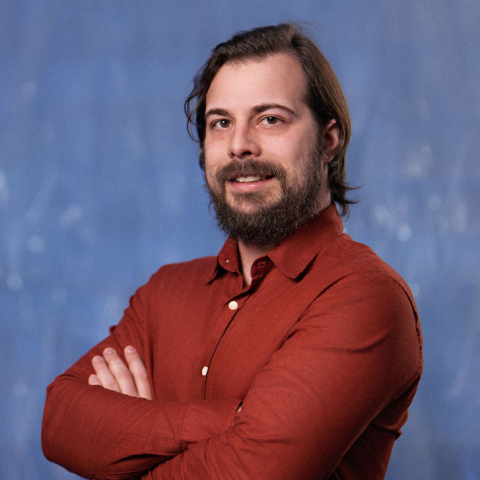 Man wih beard and using orange shirt posing.