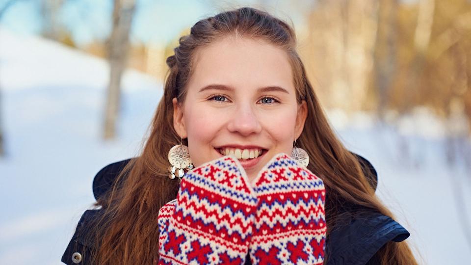 Henkilö kirjavat lapaset käsissään talvimaisemassa.