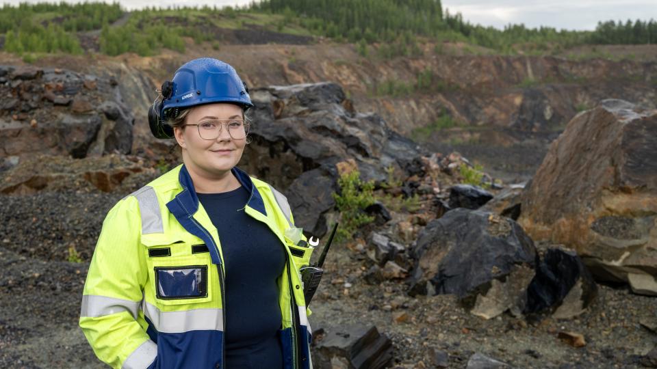 Julia Puputti seisoo työmaavaatteissa kaivoksen edustalla.