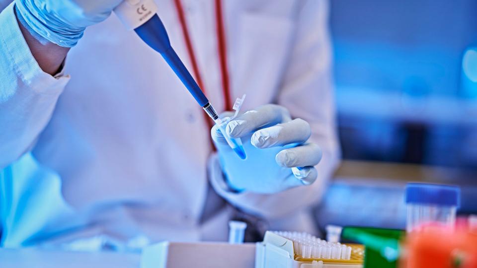 Henkilö pipetti kädessä laboratoriossa.