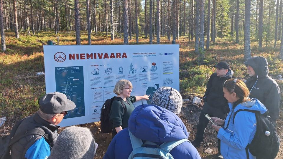 People gathered at Niemivaara sign in the forest