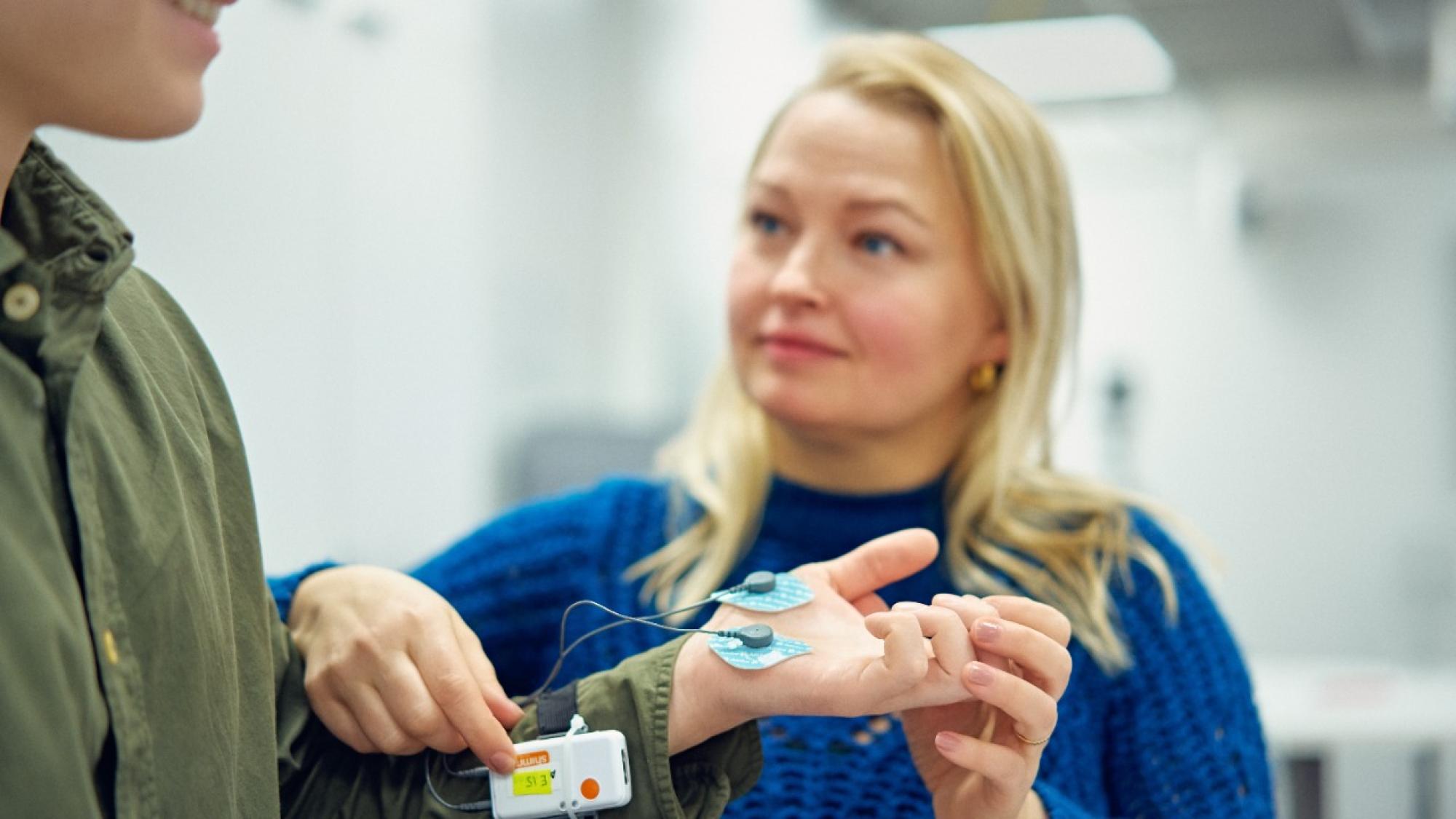 A woman putting a sensory equipment on a persons hand for measurments