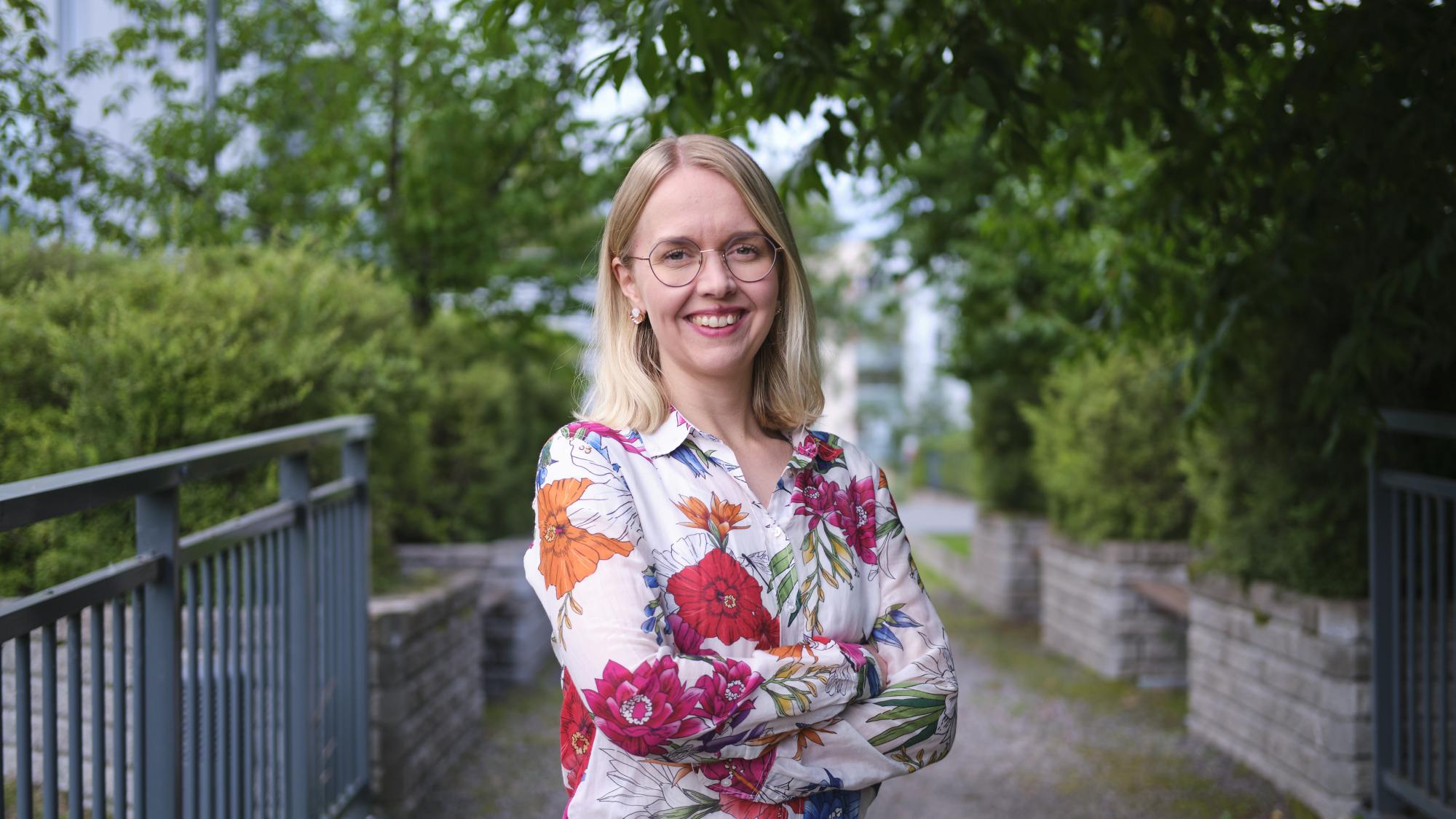 Jaana Isohätälä seisoo sillalla kesämaisemassa.