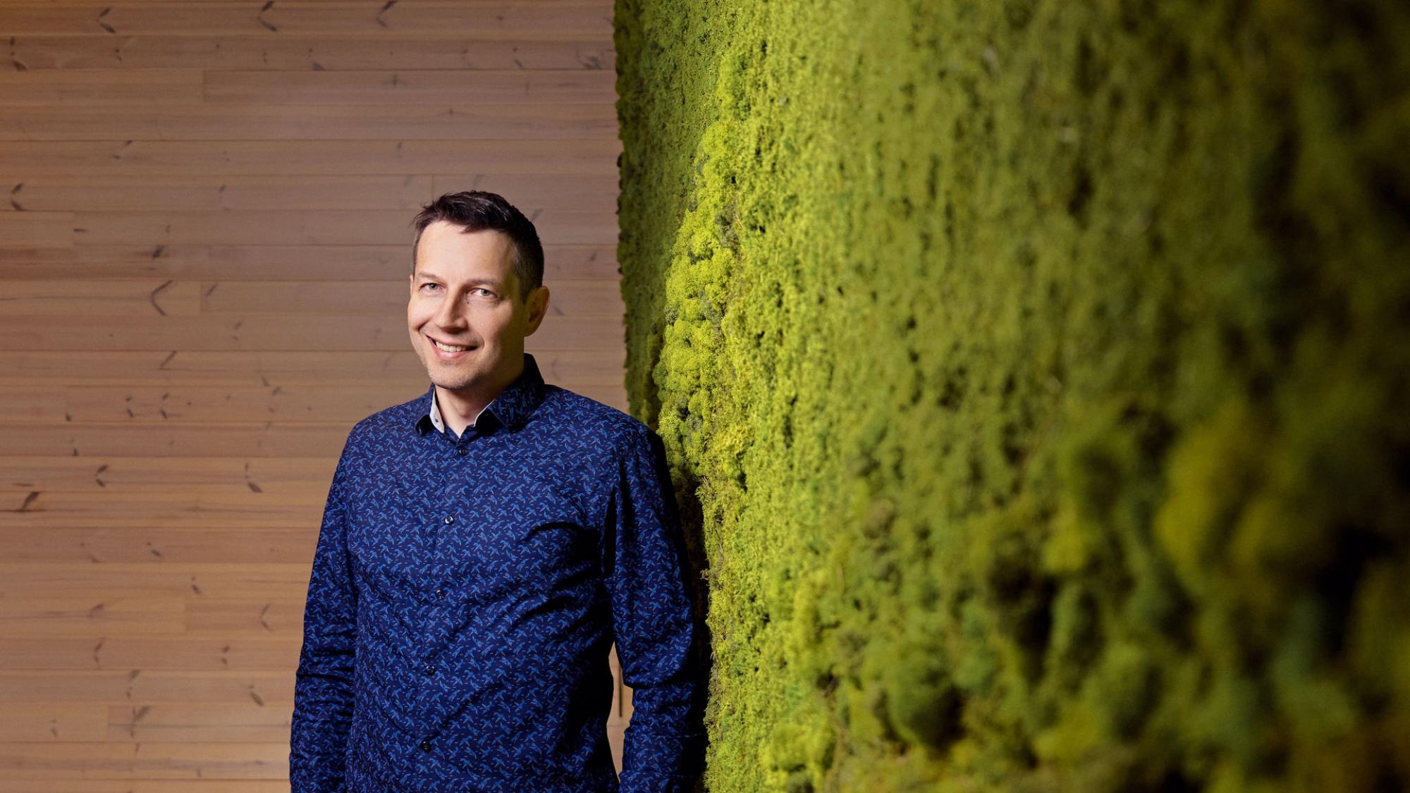 Tuotantotalouden alumni Juha Hannula nojaa vihreään sammalseinään.
