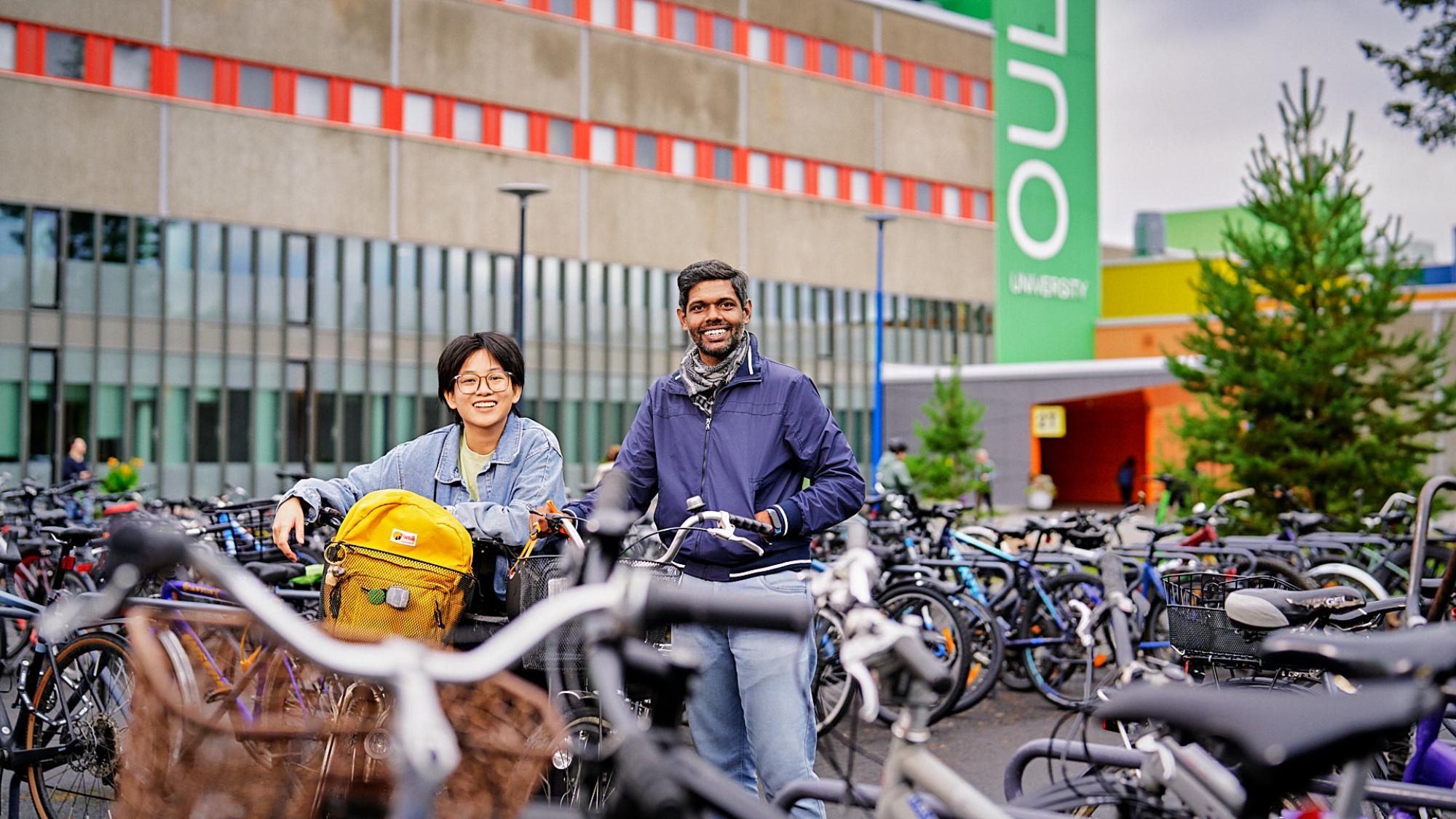 Mia Chen ja Yomal Fernando Oulun yliopiston edustalla pyöräparkkien keskellä.