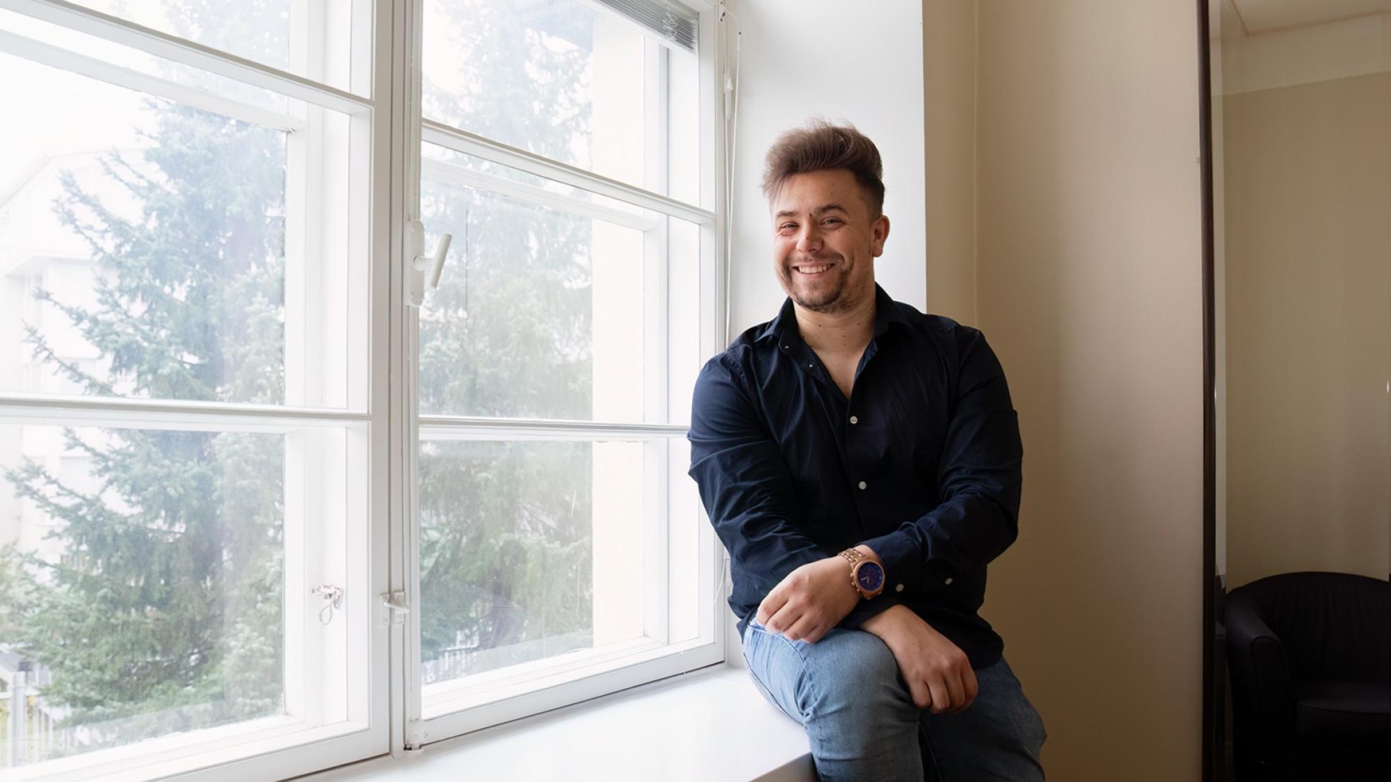 Alumni Uula Neitola istuu ikkunalaudalla.