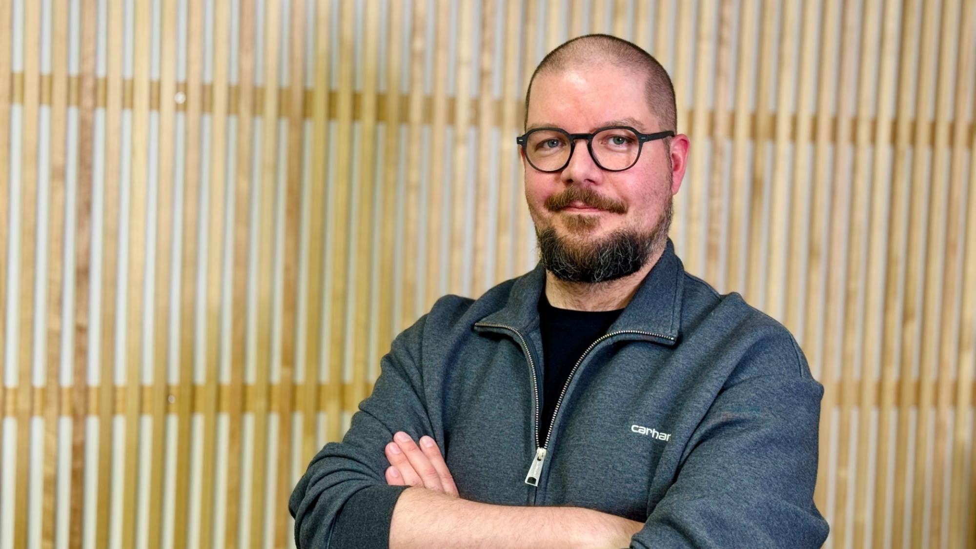 Antti Siipo in portrait with a wooden wall in the background