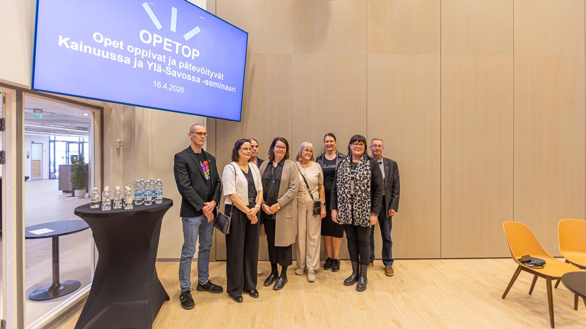 Kuvassa vasemmalta oikealle vt. Kajaanin kaupunginjohtaja Joni Partanen, Opetus- ja kulttuuriministeriön johtaja Jonna Korhonen, Kajaanin kaupunginhallituksen puheenjohtaja Minna Leinonen, Kajaanin kaupungin sivistysjohtaja Mari Selin, Iisalmen kaupungin sivistys- ja hyvinvointitoimialan johtaja Kirsi-Tiina Ikonen, Kainuun maakuntajohtaja Riikka Pirkkalainen, OPETOP-hankkeen vastuullinen johtaja Eva Raudasoja, Kajaanin kaupungin elinvoimajohtaja Risto Hämäläinen.