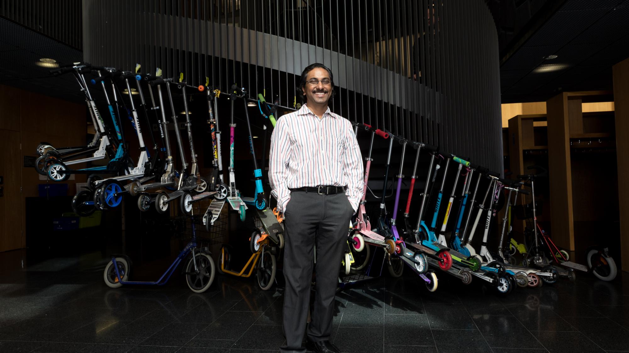 A smiling person standing in front of a stairway.