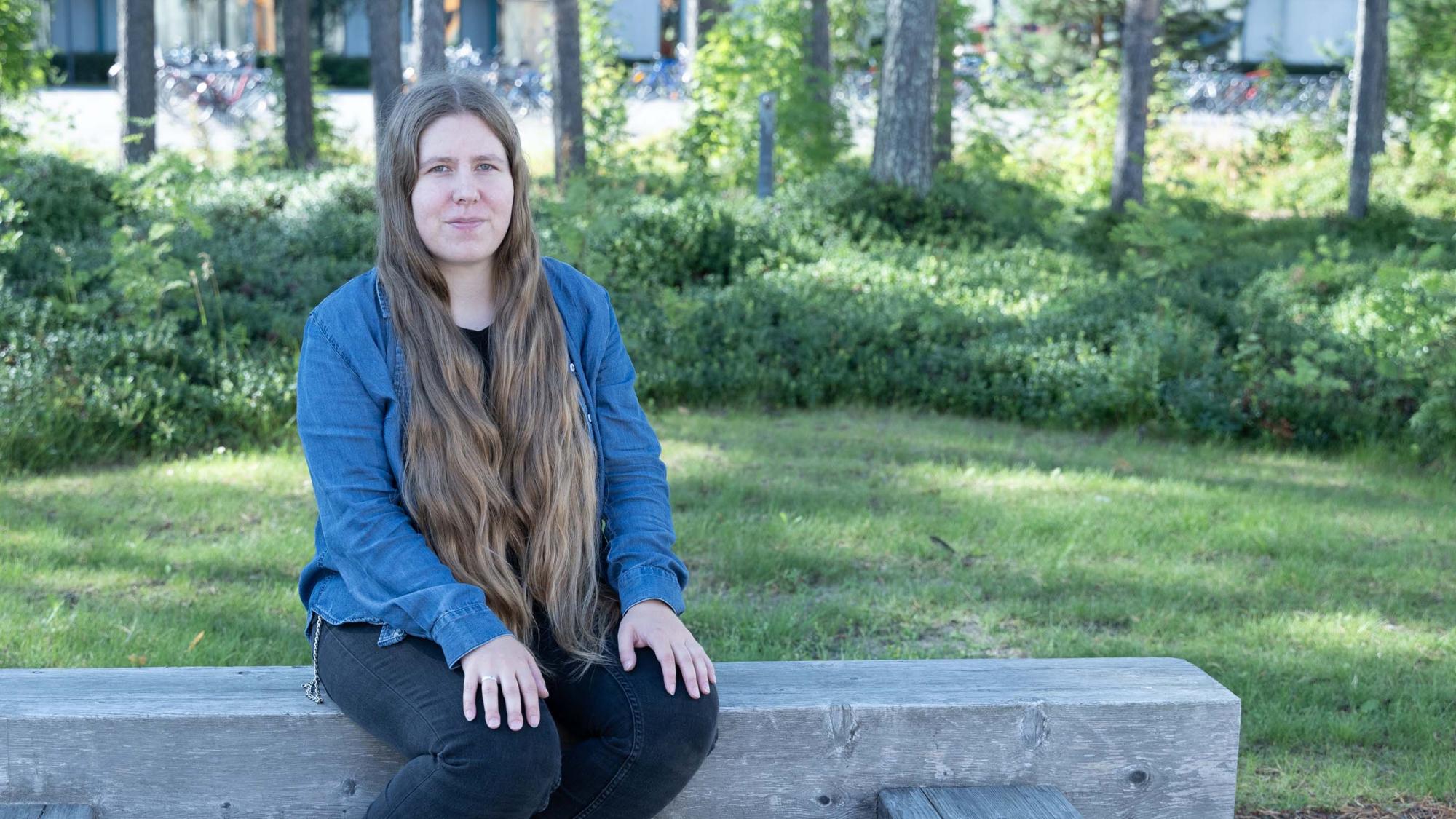 Maaria Tuisku istuu ulkona Oulun yliopiston edustalla