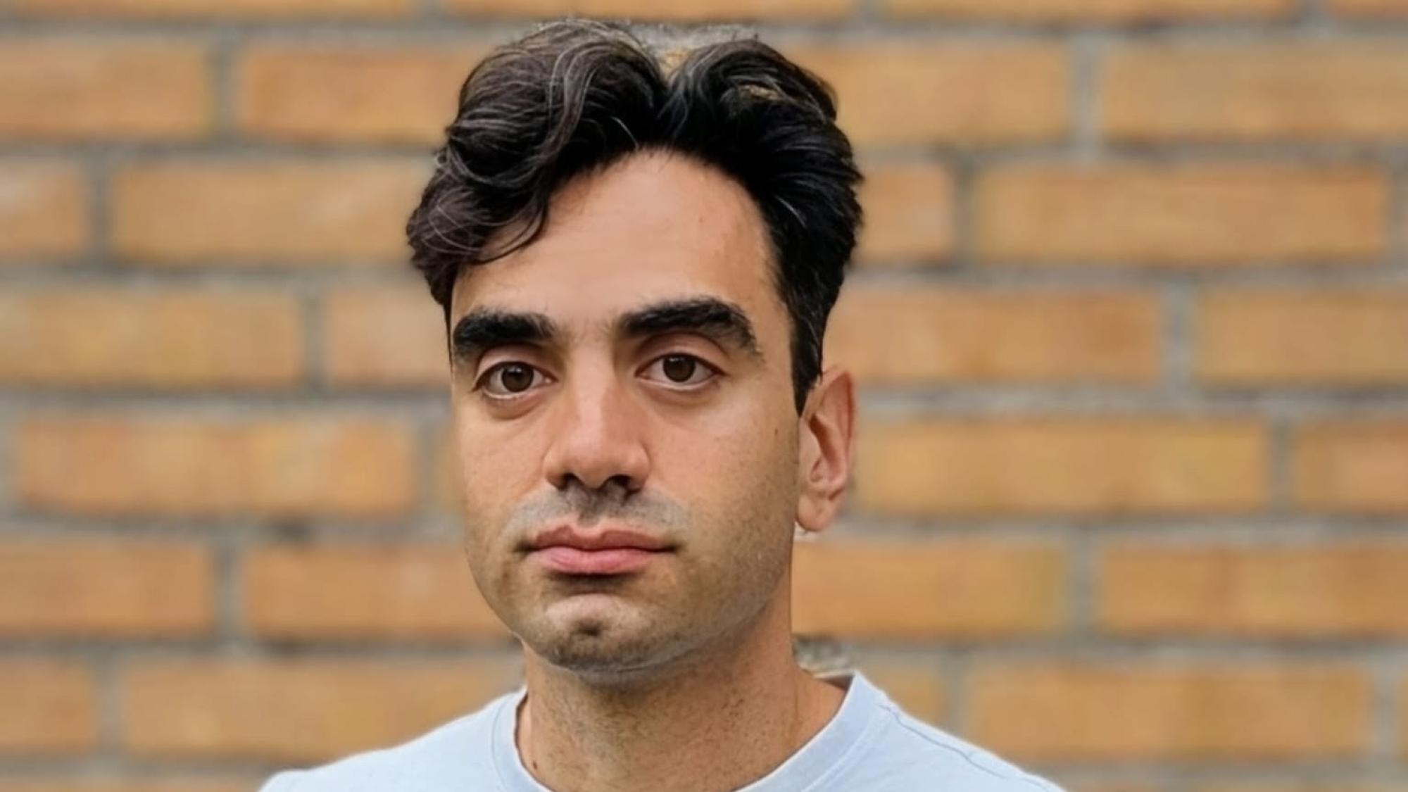 Babak Maboudi standing against a brick wall