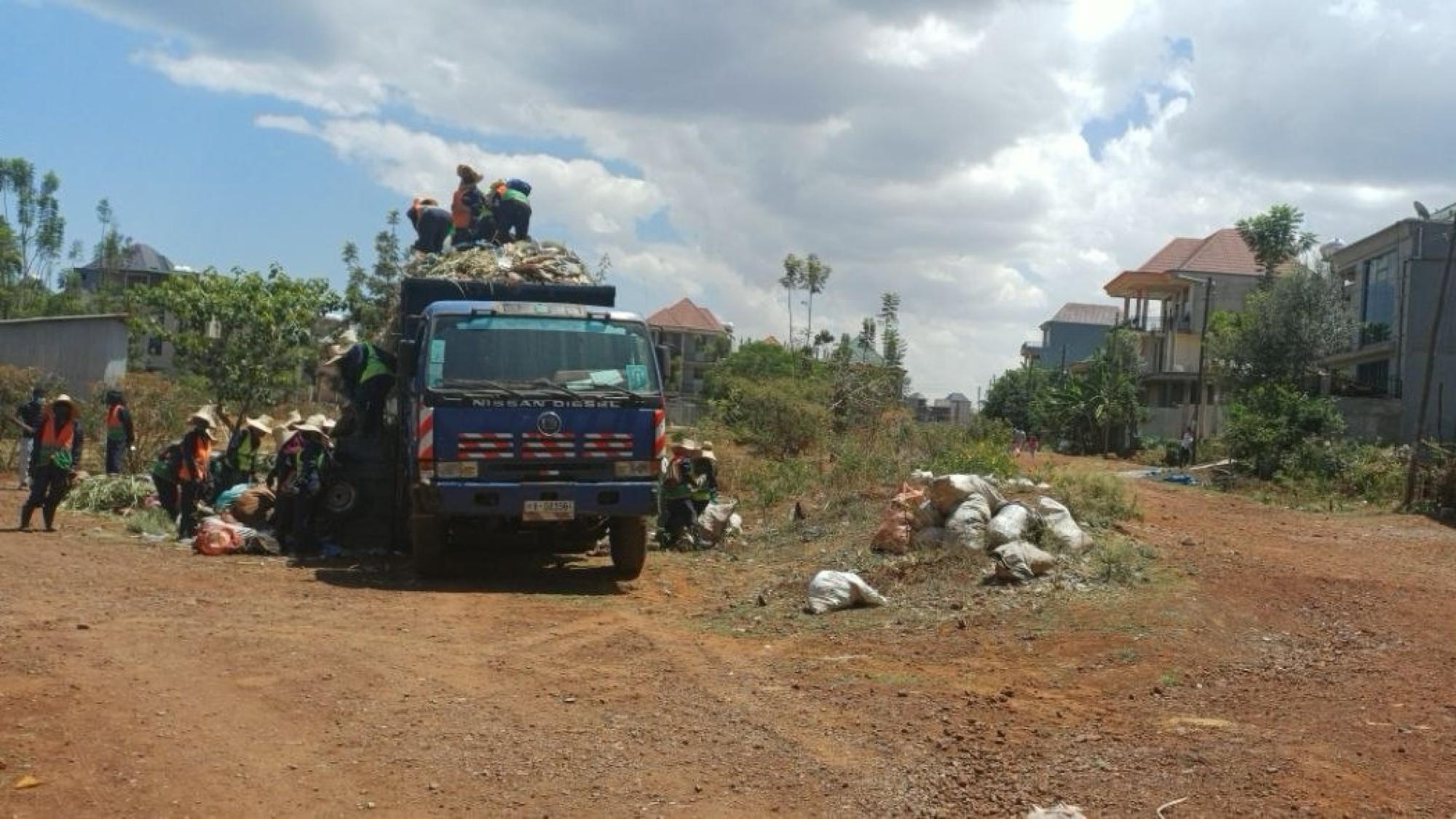 A truck with trash and people standing next to it in Ethiopia.
