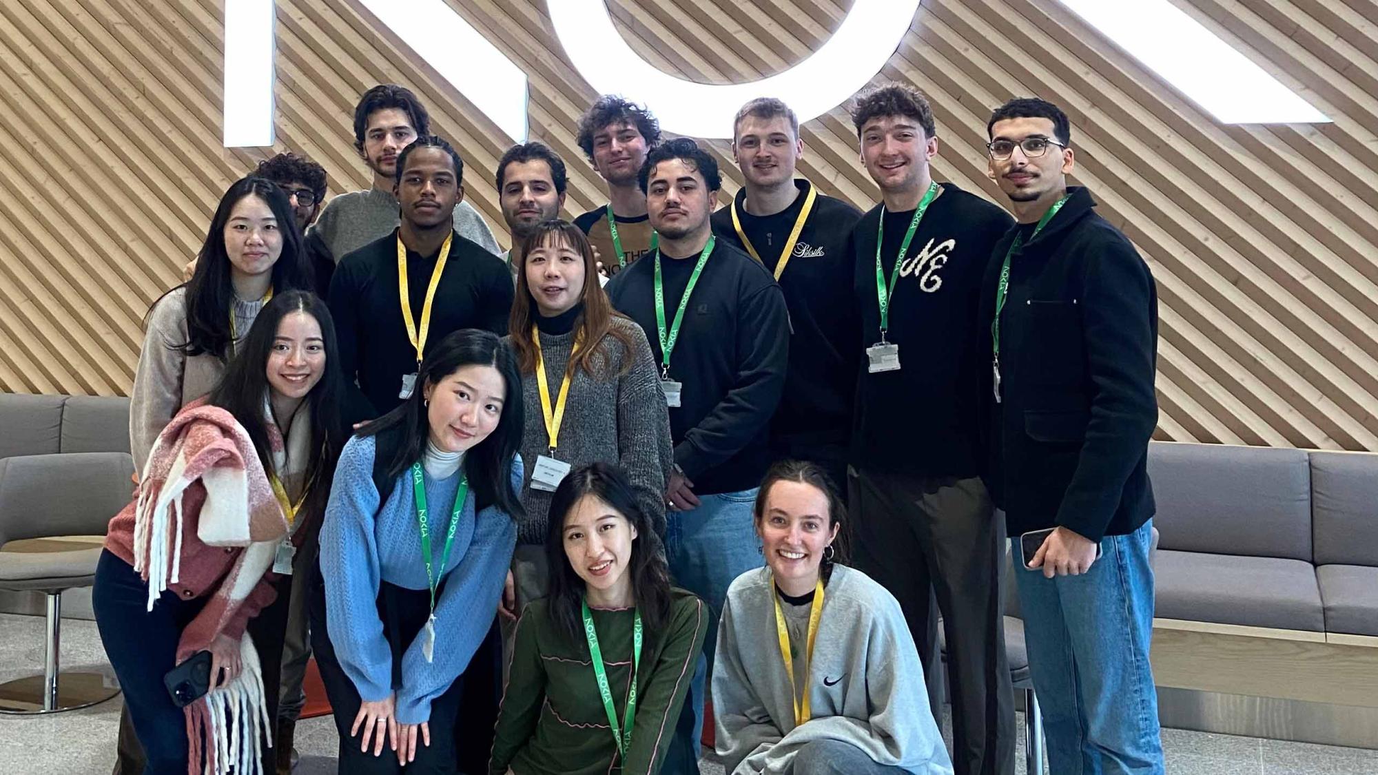 Students in a group photo in front of wooden wall with Nokia logo on it.