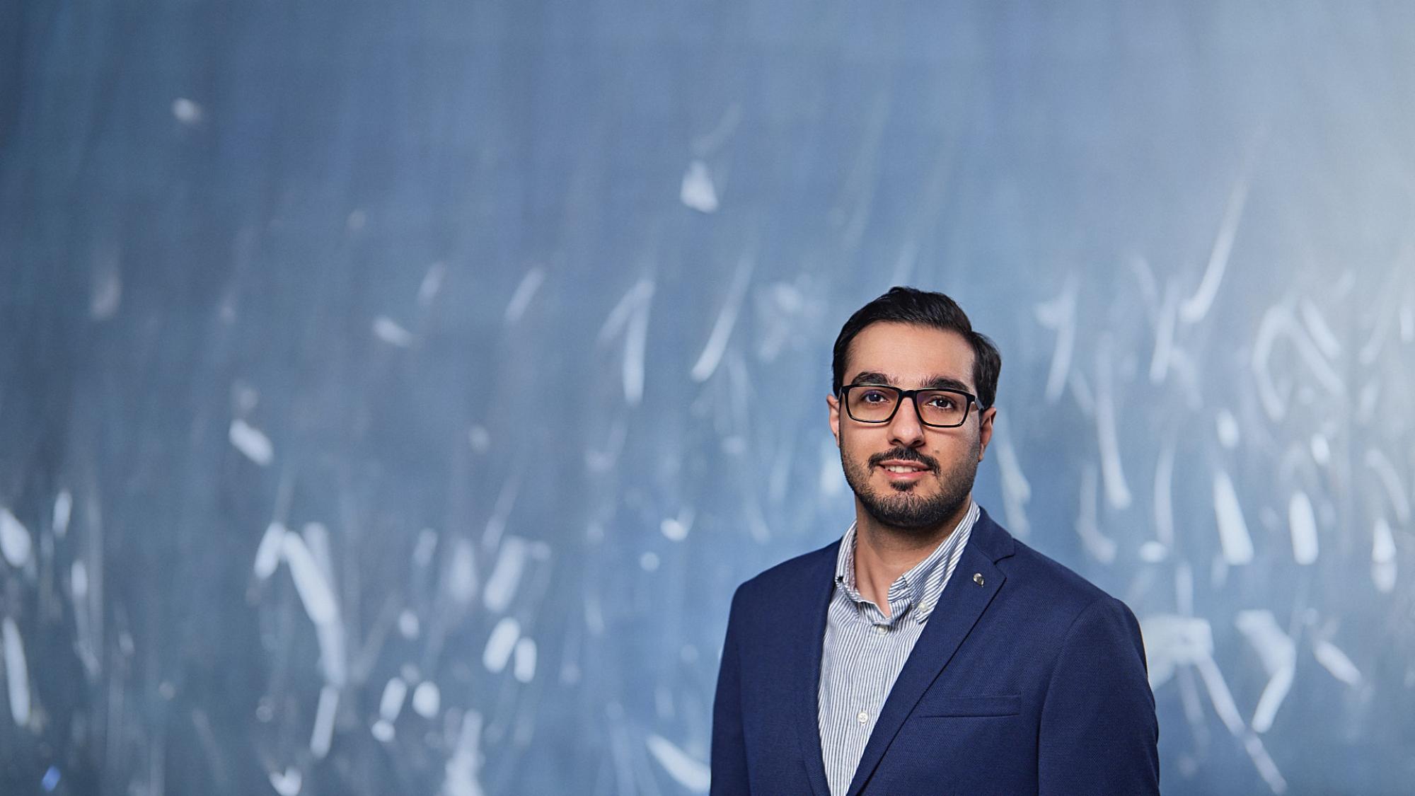 Portrait of postdoctoral researcher Aidin Heidari with blue background