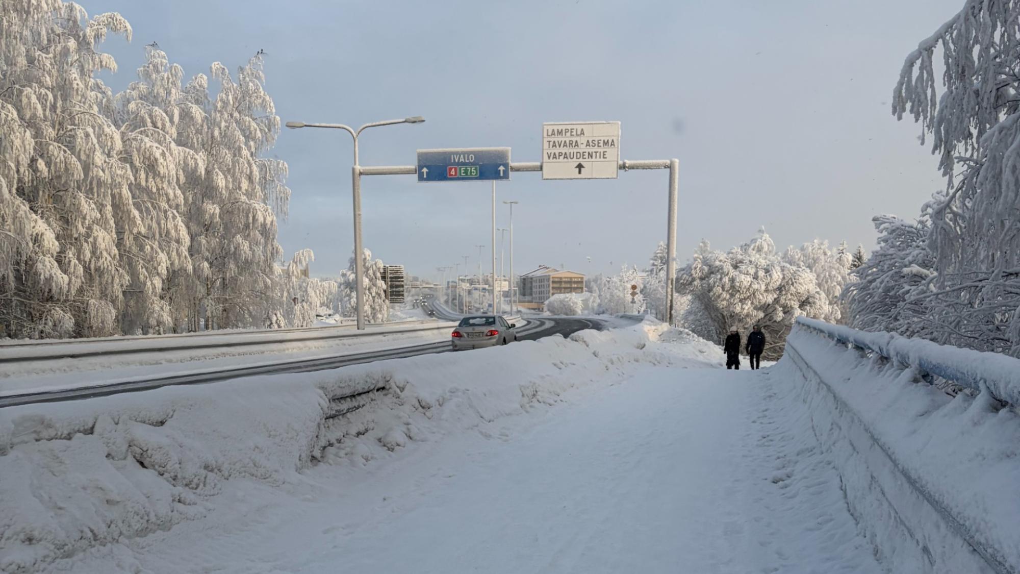 A road leading to Rovaniemi city center with some signs and very snowy landscape around