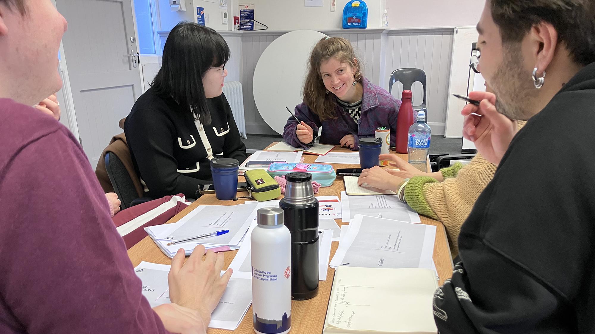 ihmisiä tekemässä ryhmätöitä pöydän ääressä