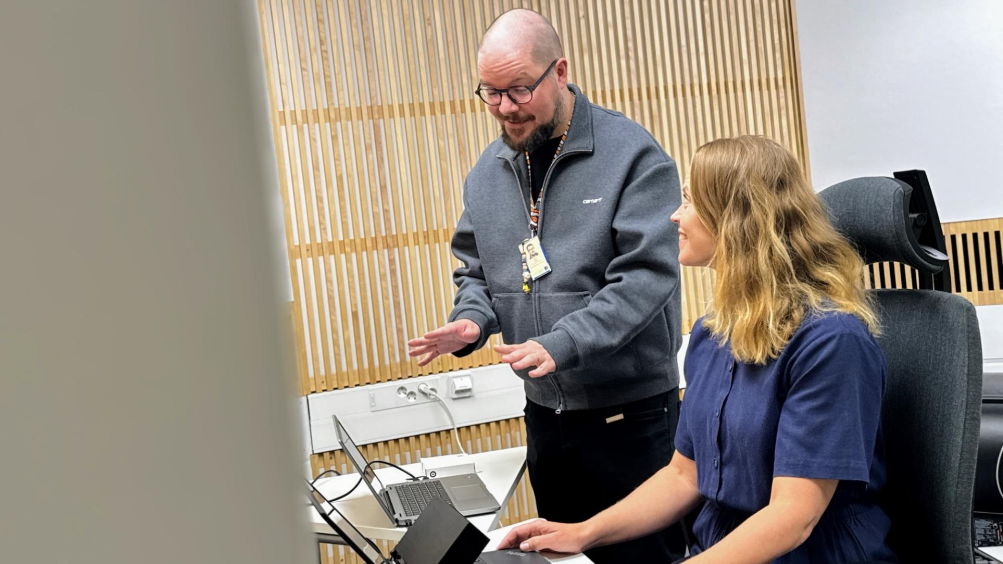 Antti Siipo and Niina Palmu in LeaF´s space using computers with wooden walls in the background.