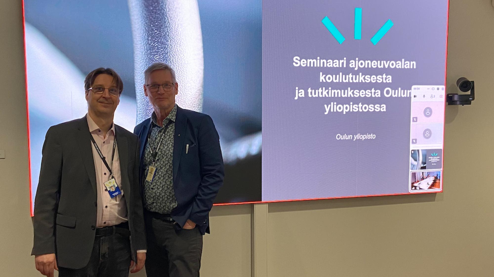 Jouni Juntinen and Sakari Jussi-Pekka posing in front of a screen.