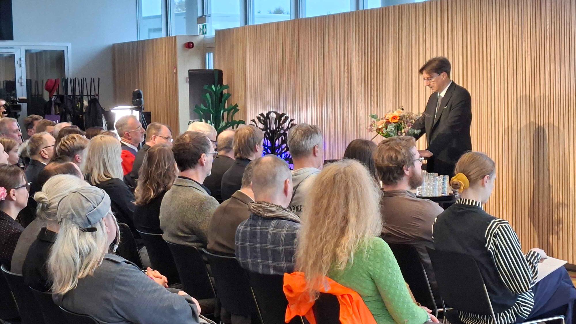 Professor Jouni Juntunen giving a speach in front of an audience.
