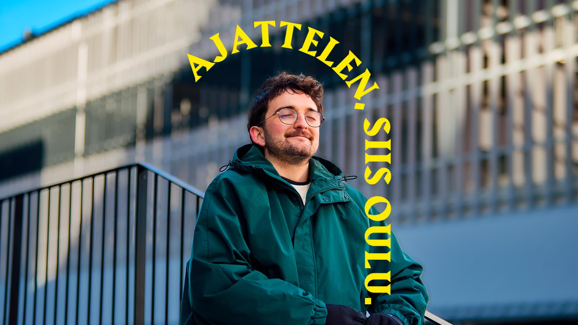 Silmälasipäinen mies vihreässä takissa istuu silmät kiinni portailla. Hänen takanaan on aita ja rakennus. Päähenkilön yläpuolella on keltainen kaari, jossa lukee Ajattelen, siis Oulu.