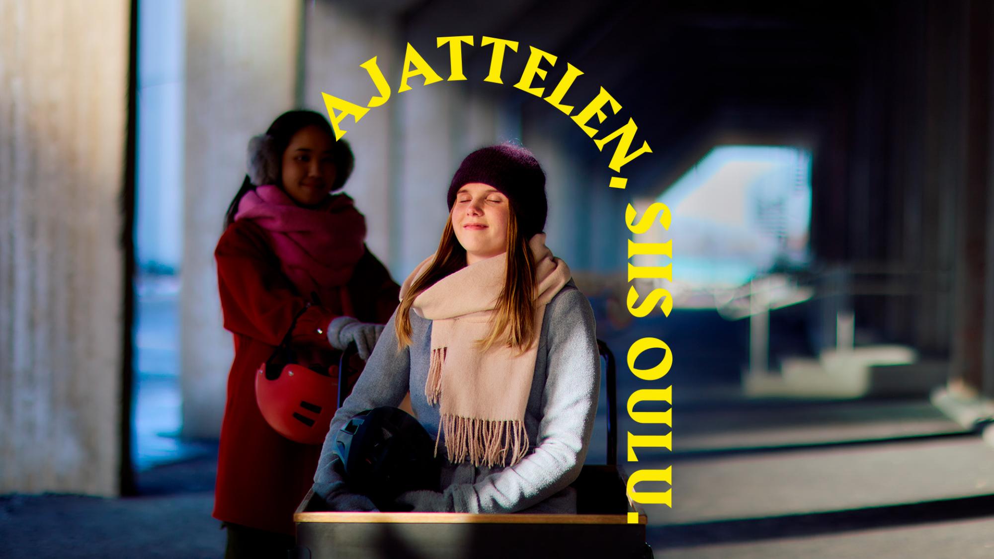 Huivi- ja pipopäinen nainen istuu silmät kiinni pyöräkärryssä. Hänen takanaan on varjossa toinen ihminen. Päähenkilön yläpuolella on keltainen kaari, jossa lukee Ajattelen, siis Oulu.