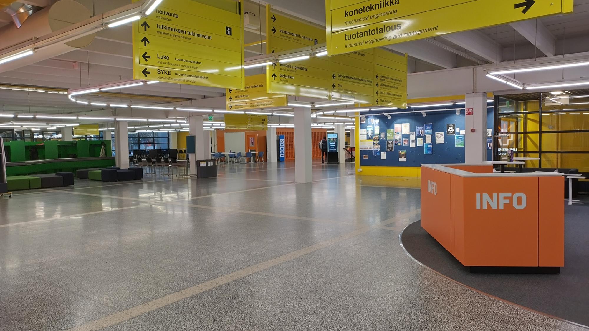 Oulun yliopiston keskusaula, jossa vasemmalla vihreät naulakot ja oikealla oranssi infopiste.