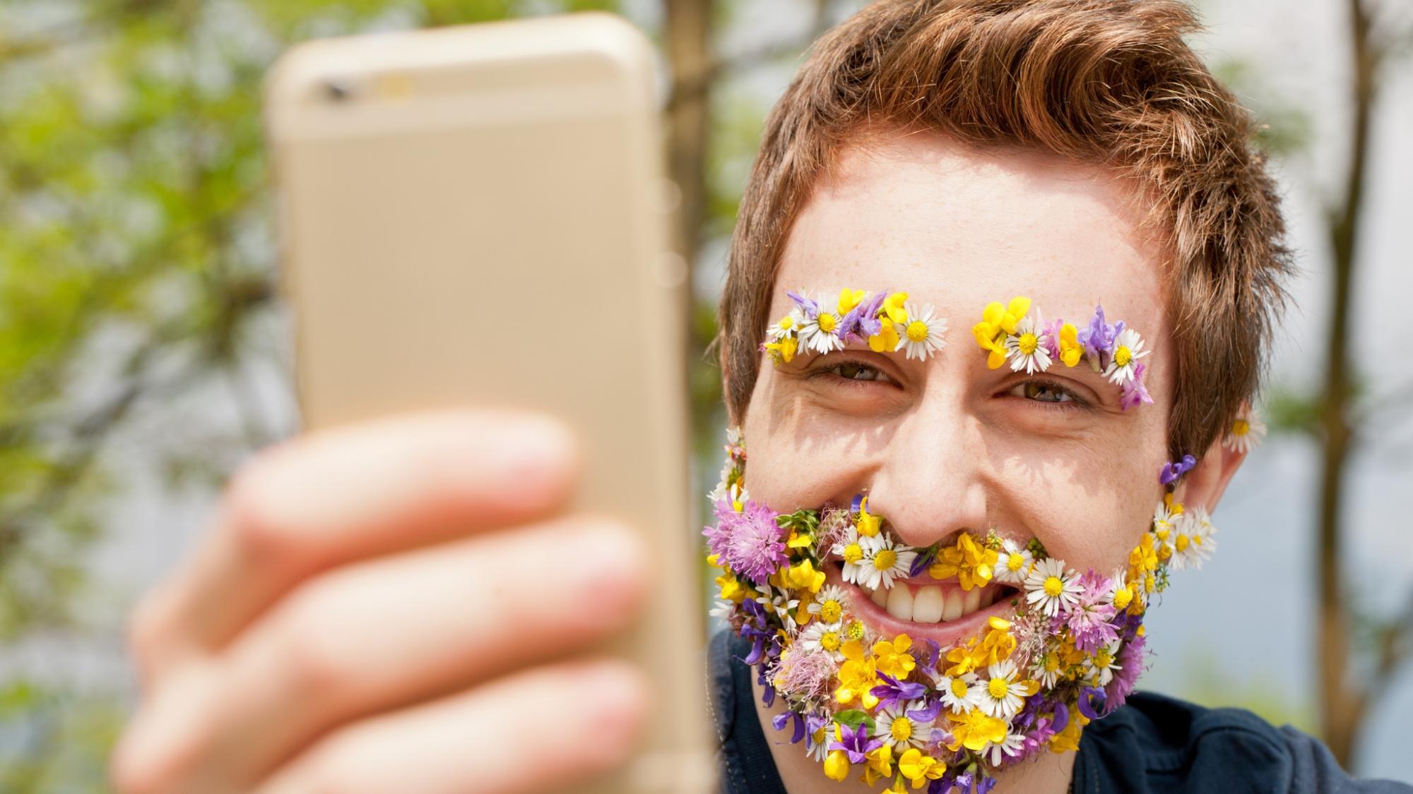 kukkapartainen mies pitelee kännykkää