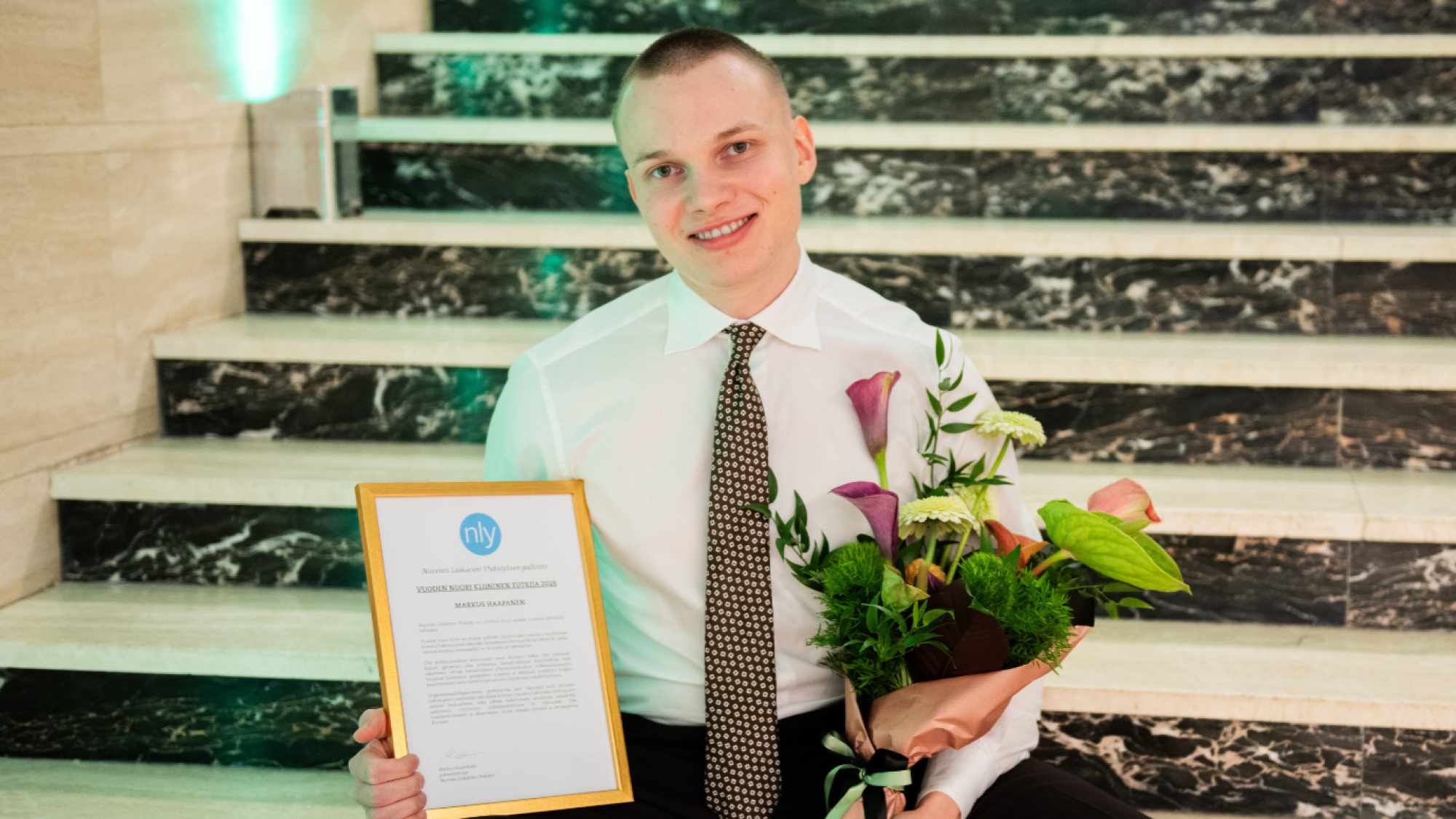 Markus Haapanen diplomi ja kukkakimppu käsissään.