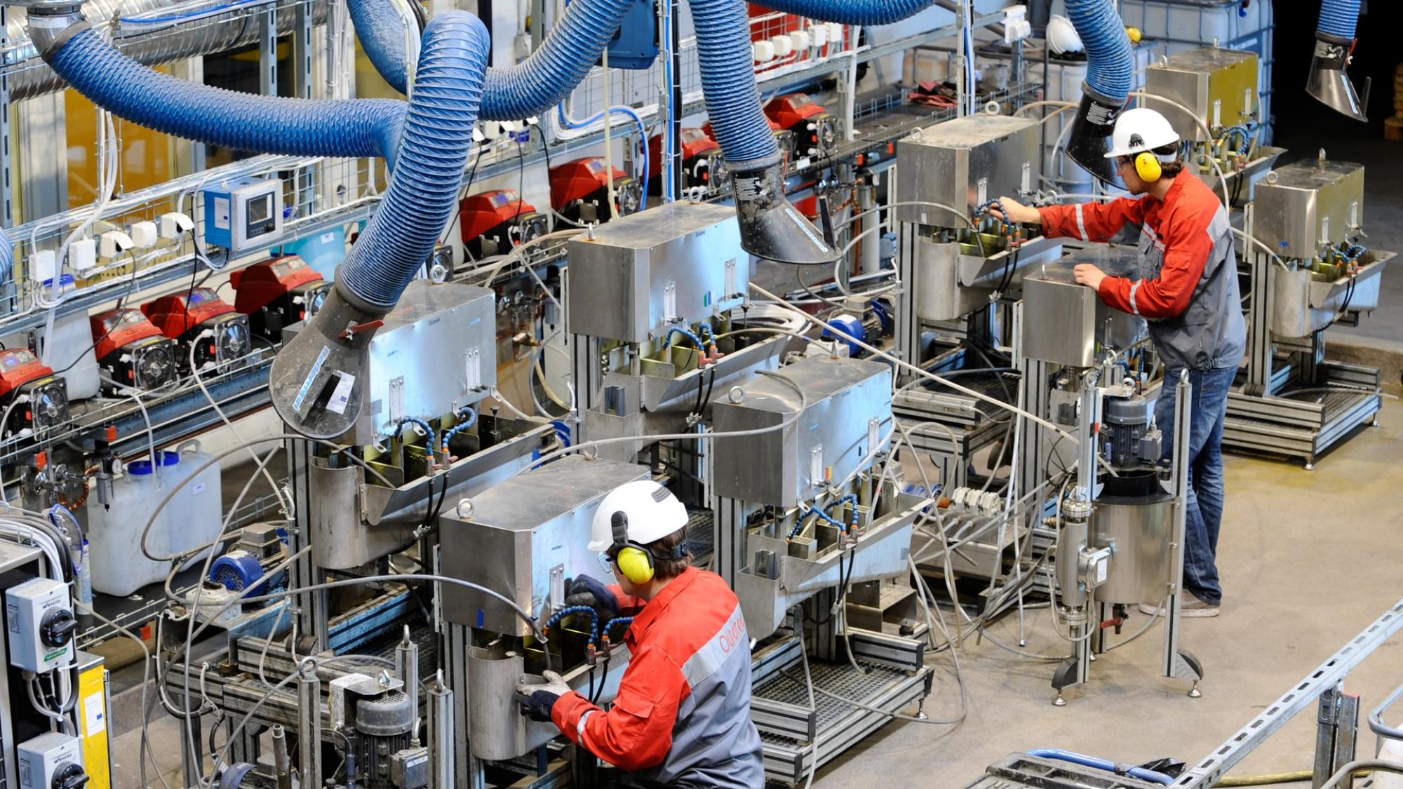 Kaksi miestä työskentelee koneiston parissa