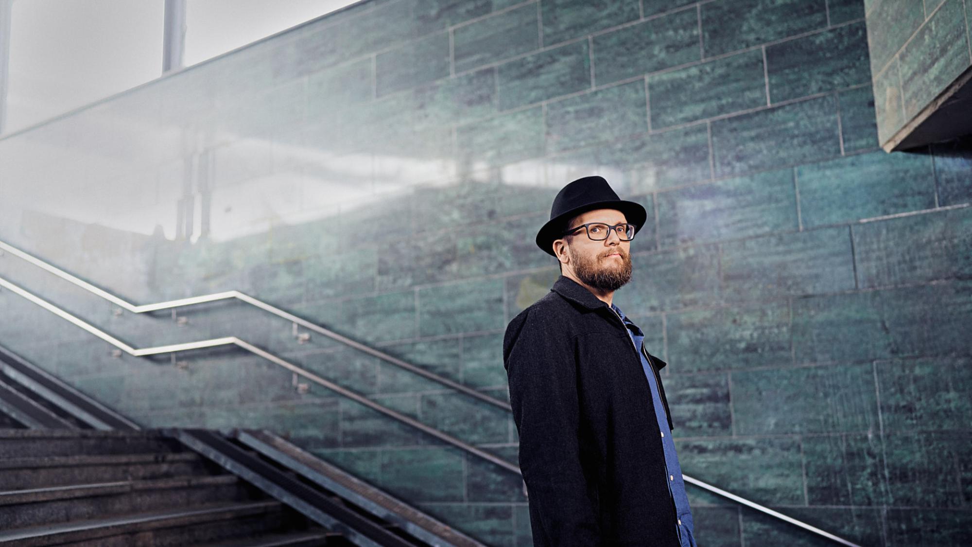 Mies hattu päässä seisoo rautatietunnelissa.