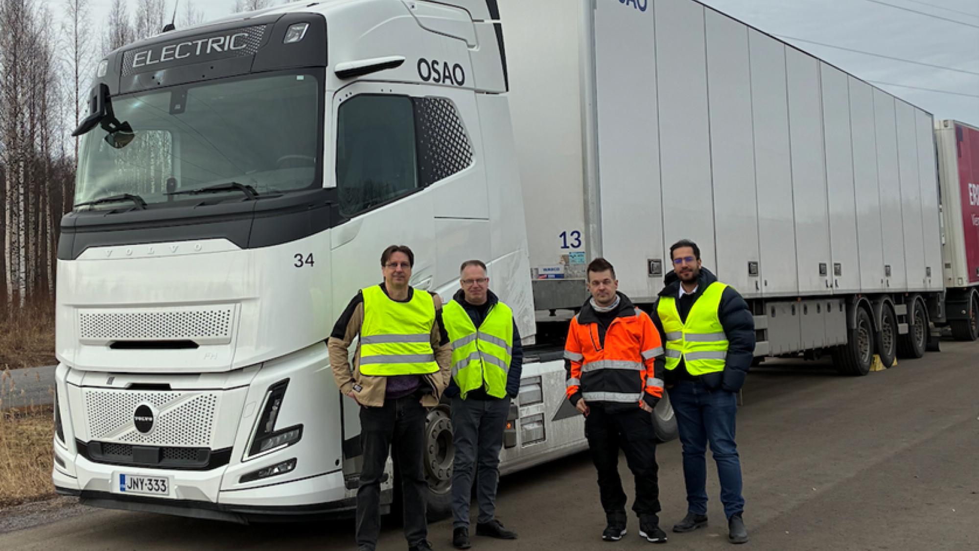 Four men standing in front of a white electric truck.