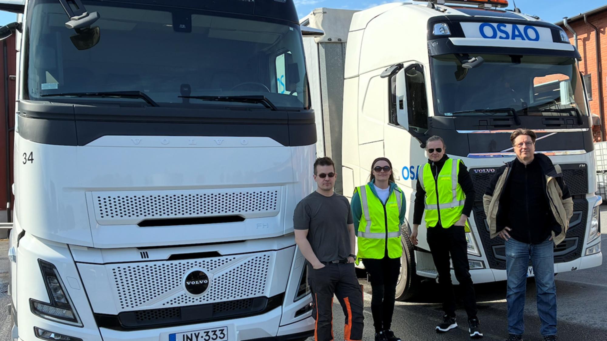 Four people standing in front of two white trucks.