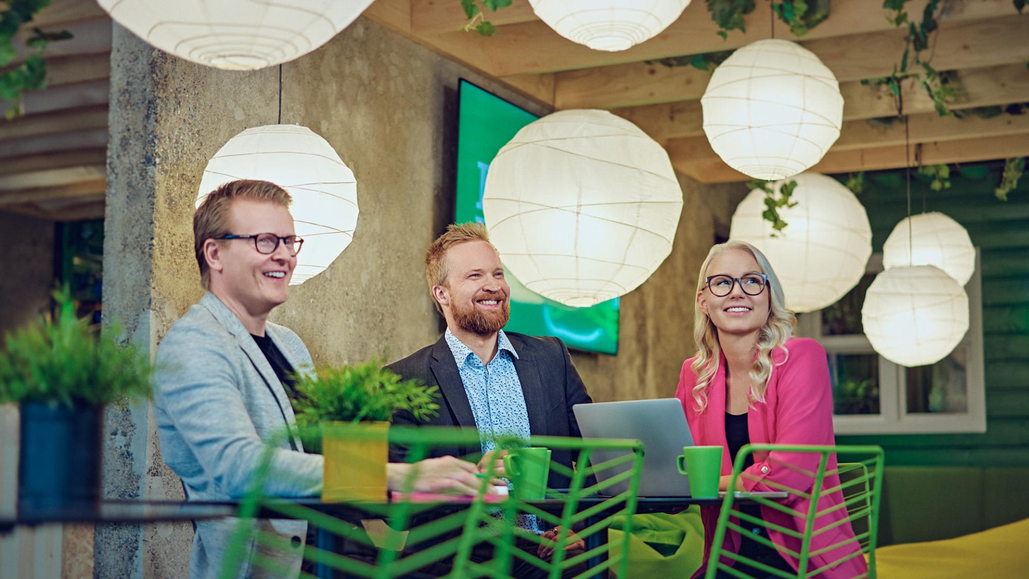 Three people sitting at a table in colorful surroundings.