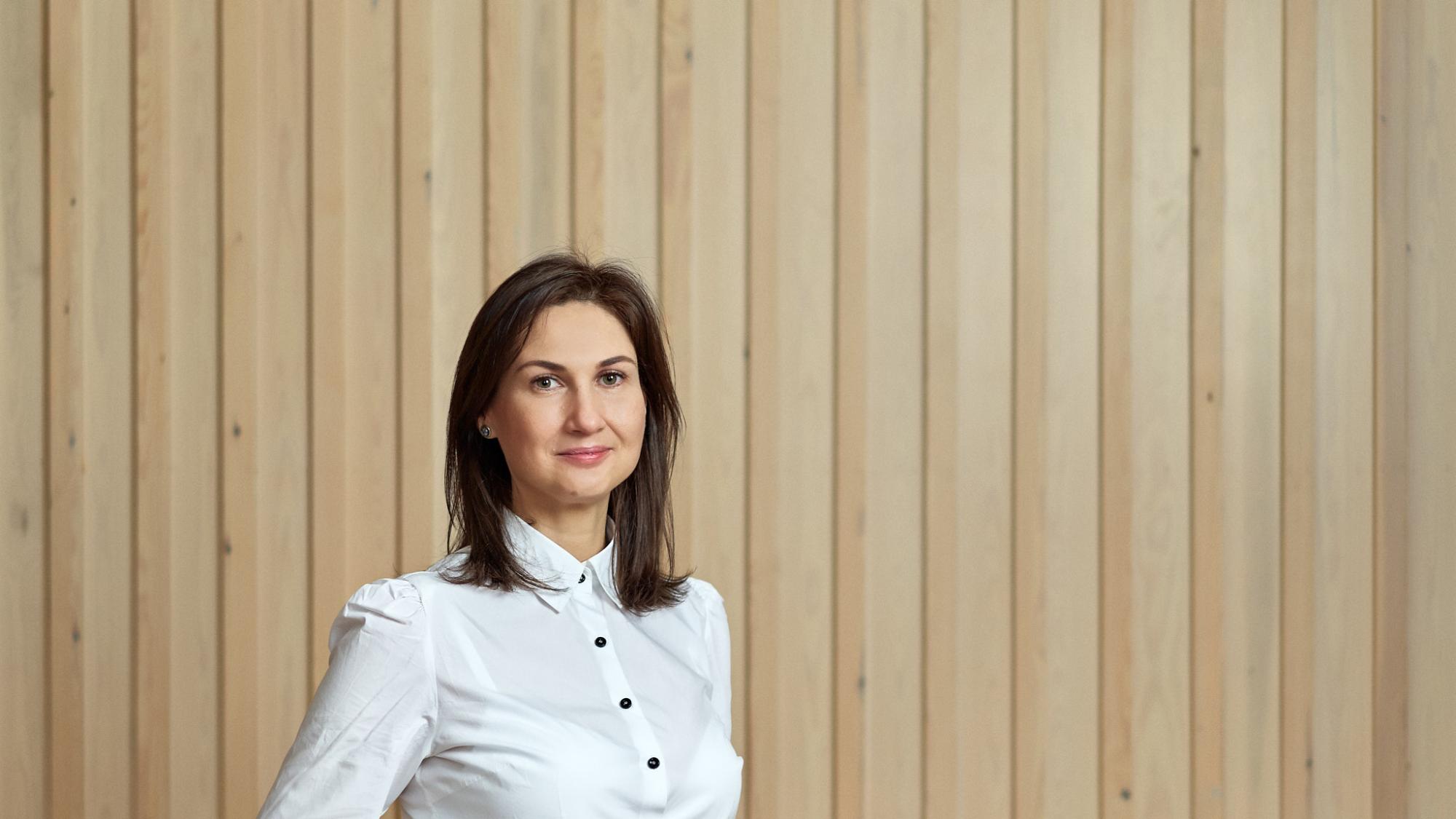 Oxana Gisca standing in front of wooden panel wall