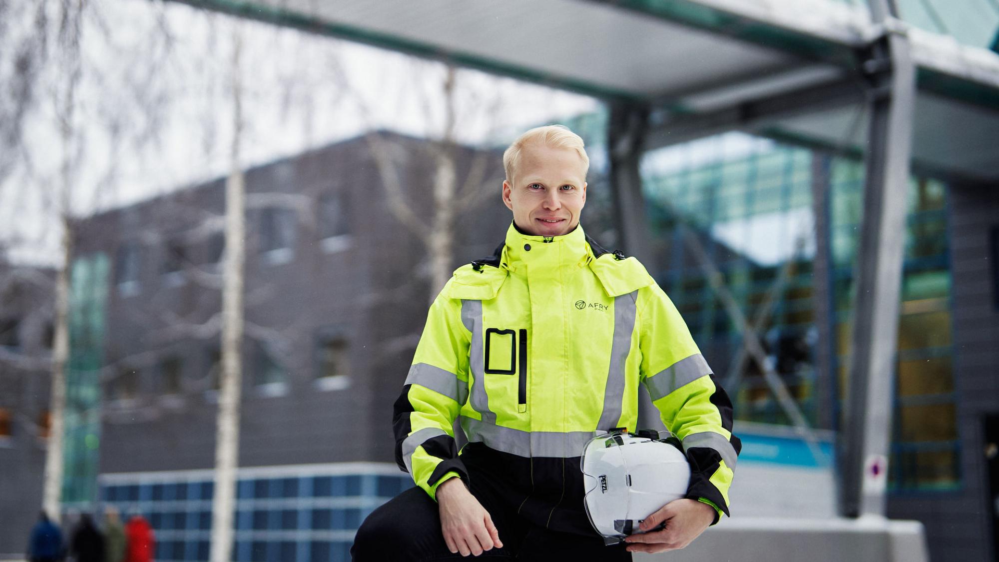 Alumni Mika Petäjäjärvi seisoo ulkona työtakki ja kypärä päässä.