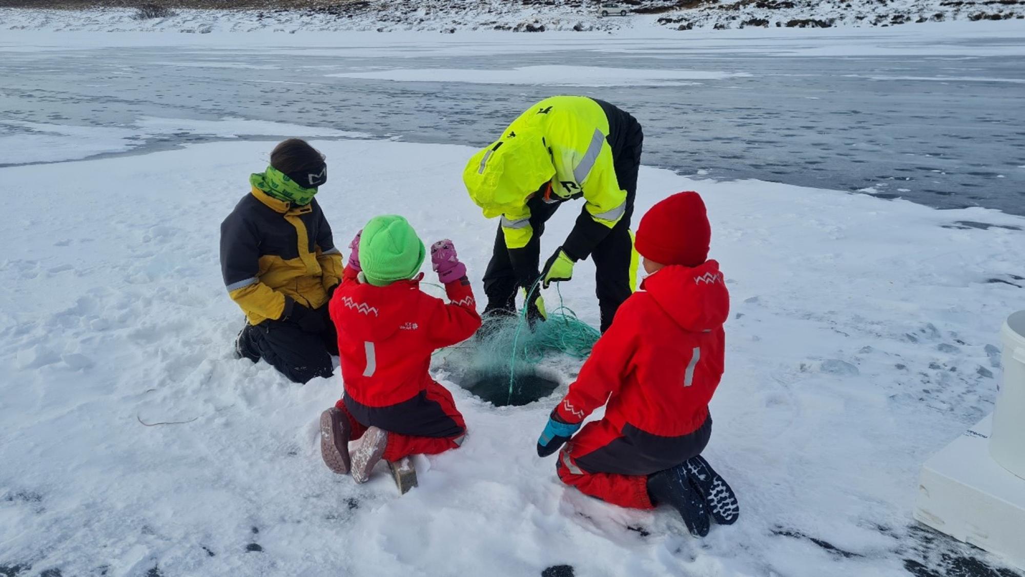People on the ice of a river ice hole fishing.