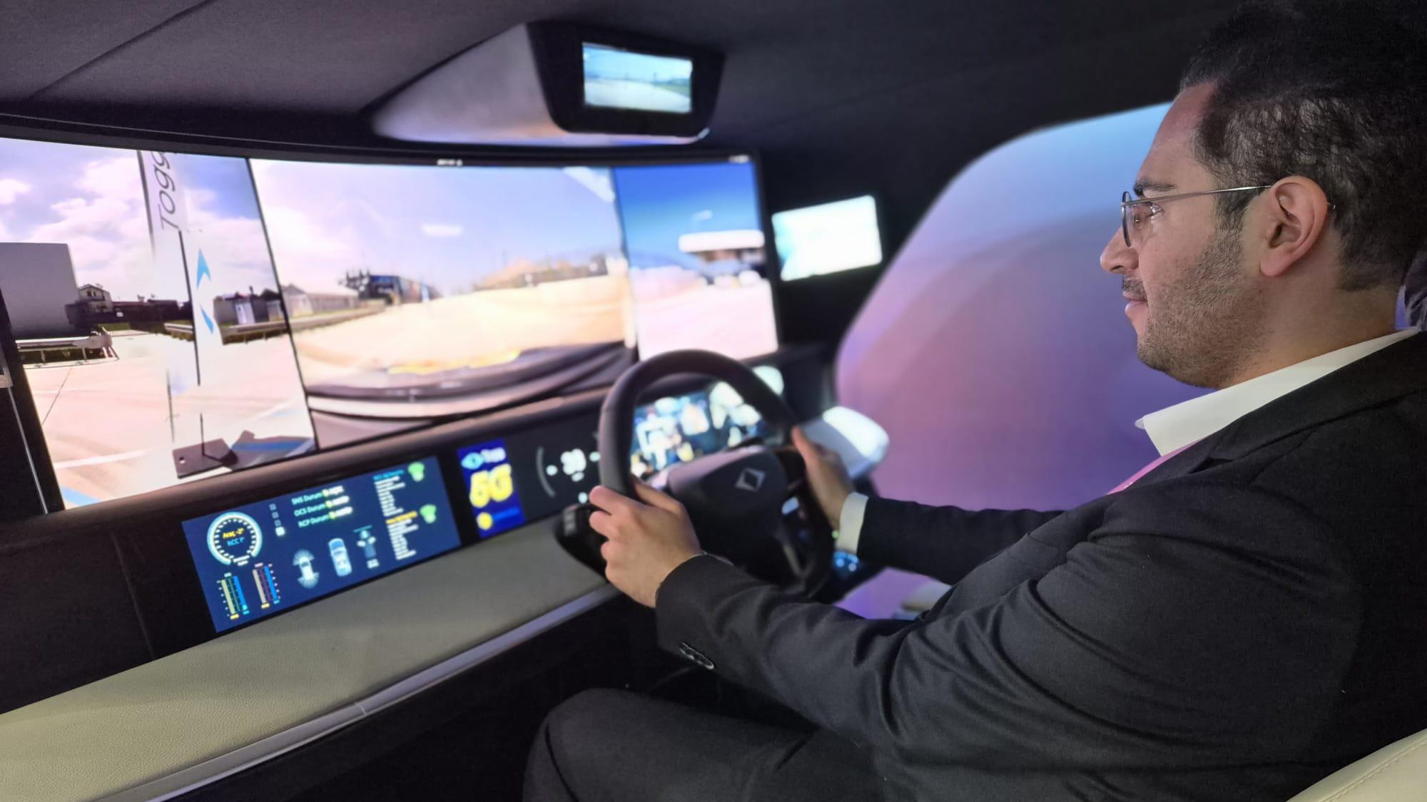 A man inside a driving simulator holding on to a steering wheel and looking at the screens.