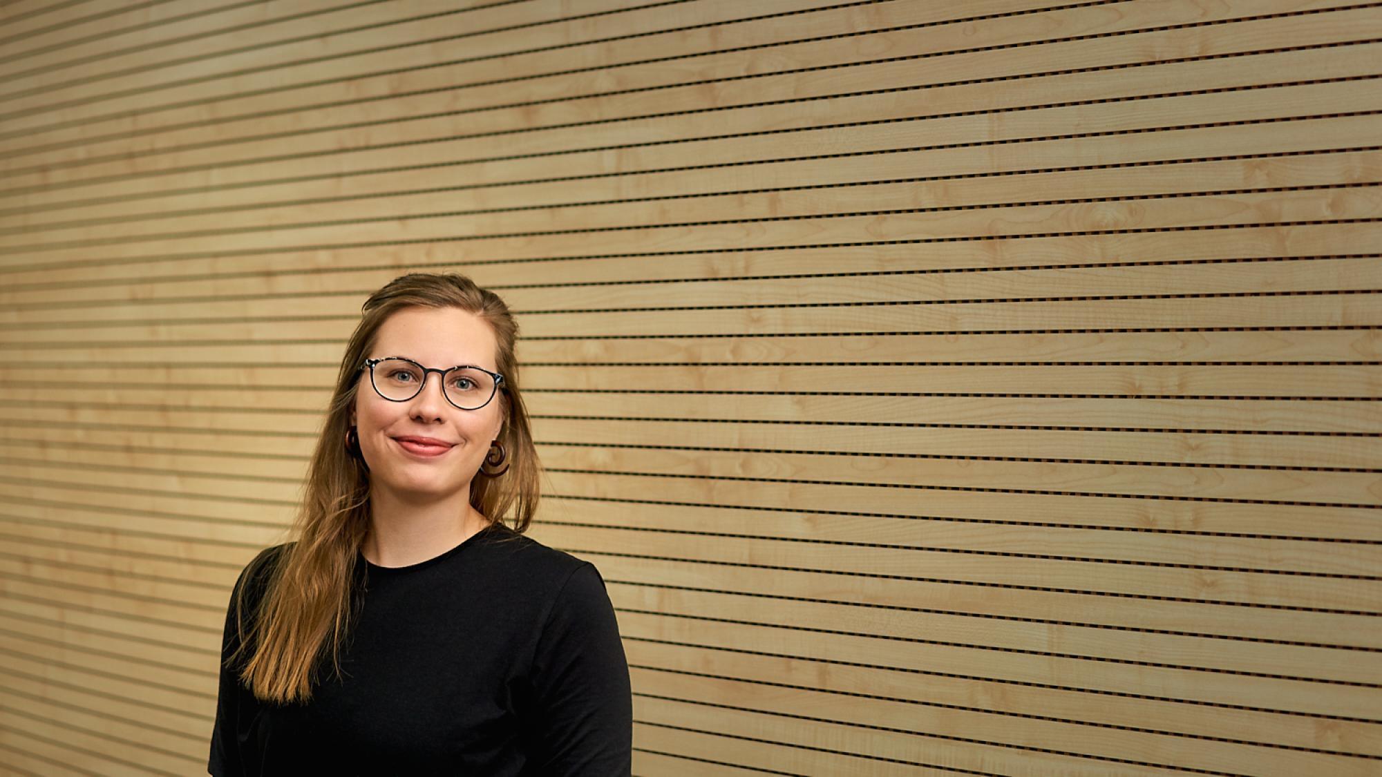 Profile photo of Maija Toivanen smiling with a wooden colored wall in the background
