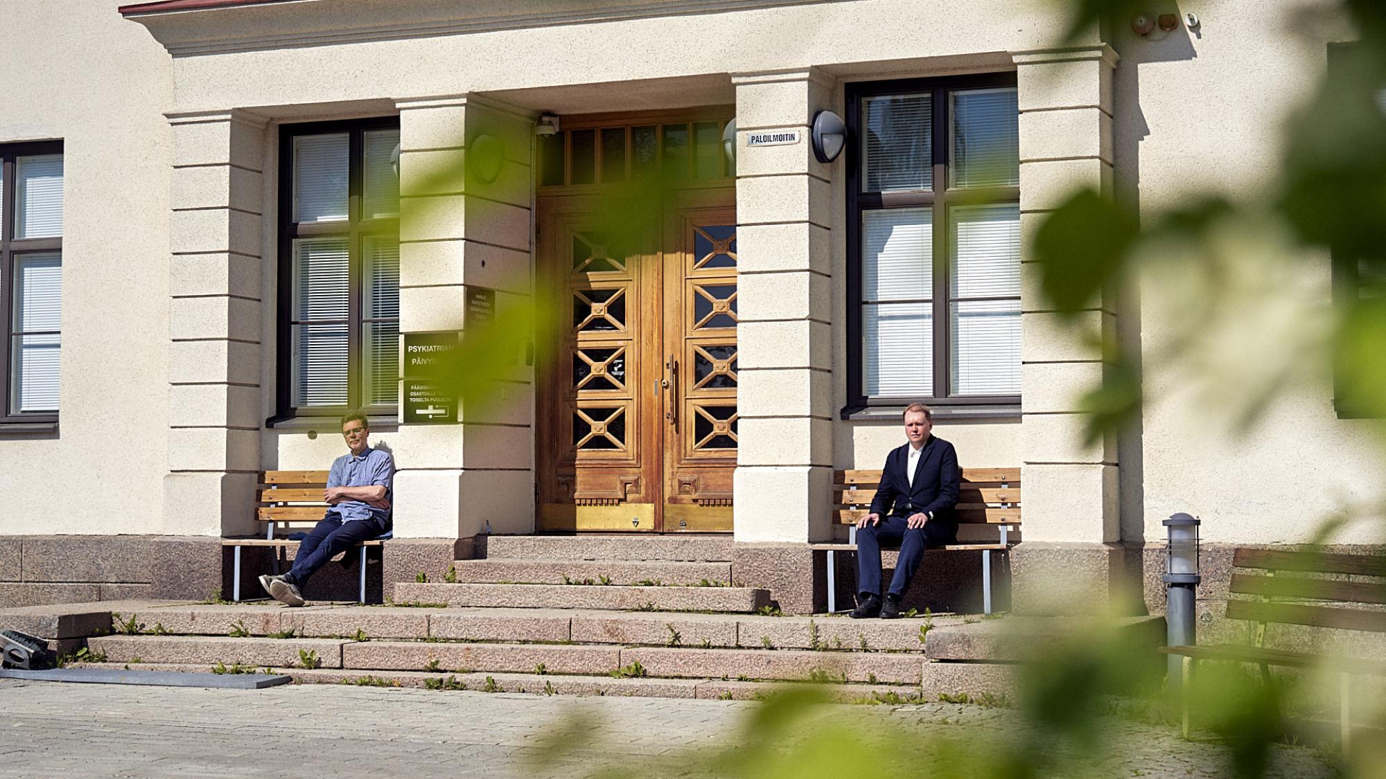 Professori Petteri Pietikäinen ja tutkijatohtori Samu Sarviaho kuvattuna sairaalarakennuksen sisäänkäynnin edessä.