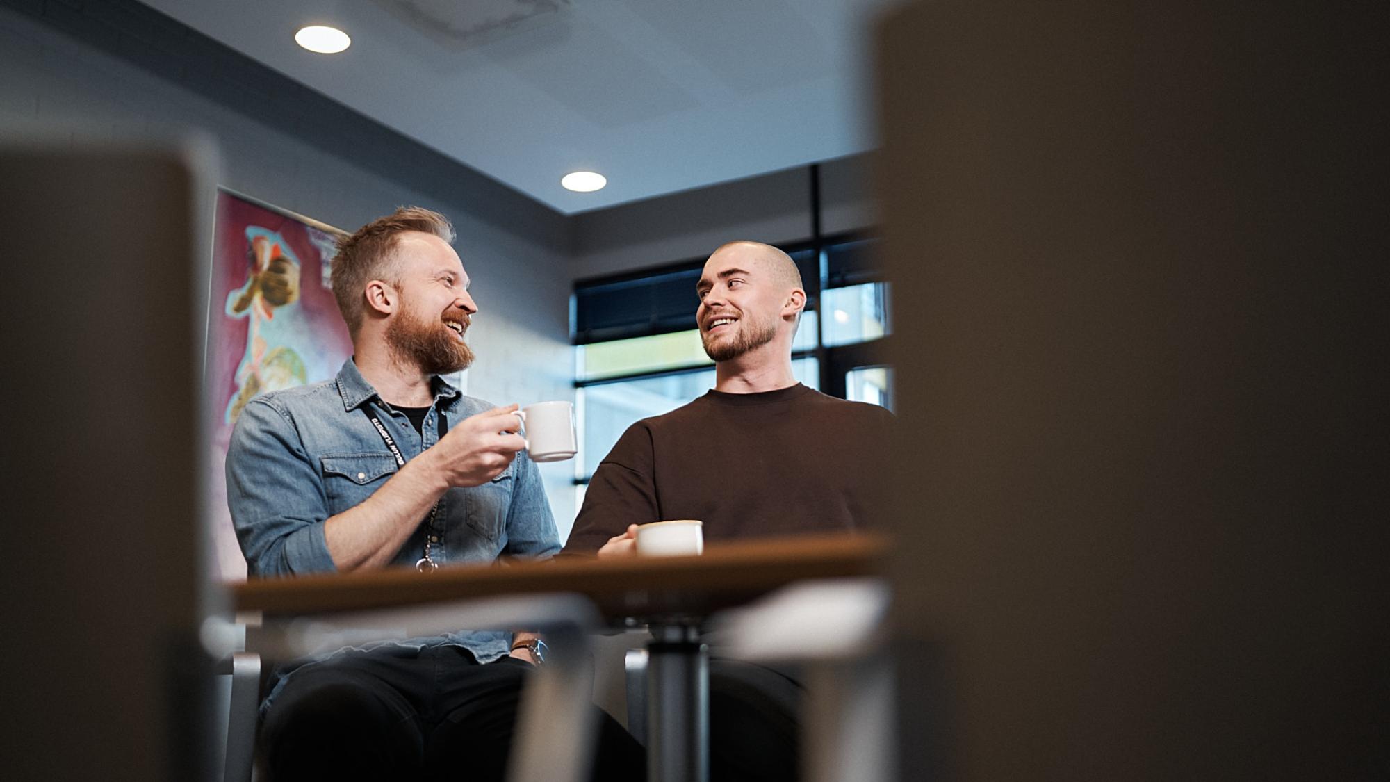 Tero Huhtala and Tori Keränen discuss and hold coffee cups.