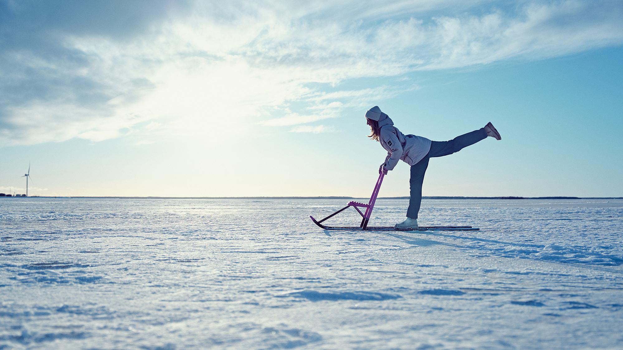 nainen taiteilee potkukelkalla jäällä