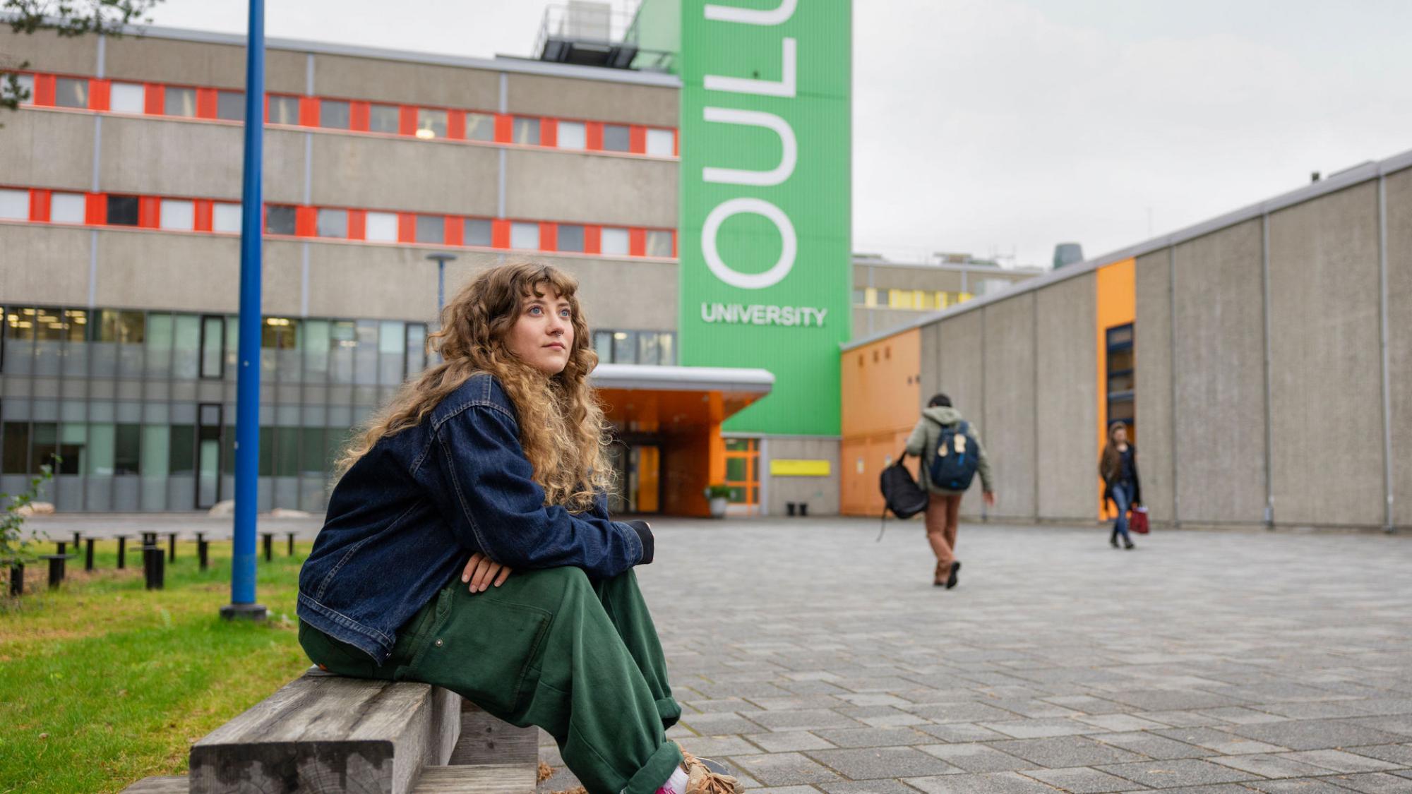 A woman sitting in front of the university.
