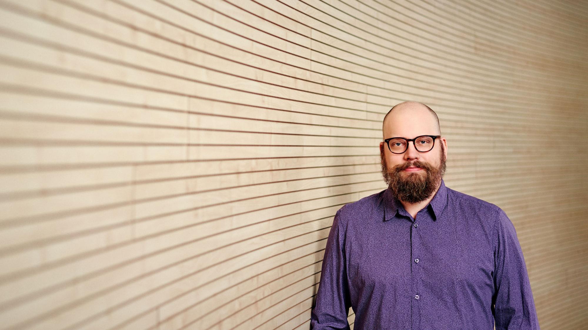A person standing next to wooden wall.
