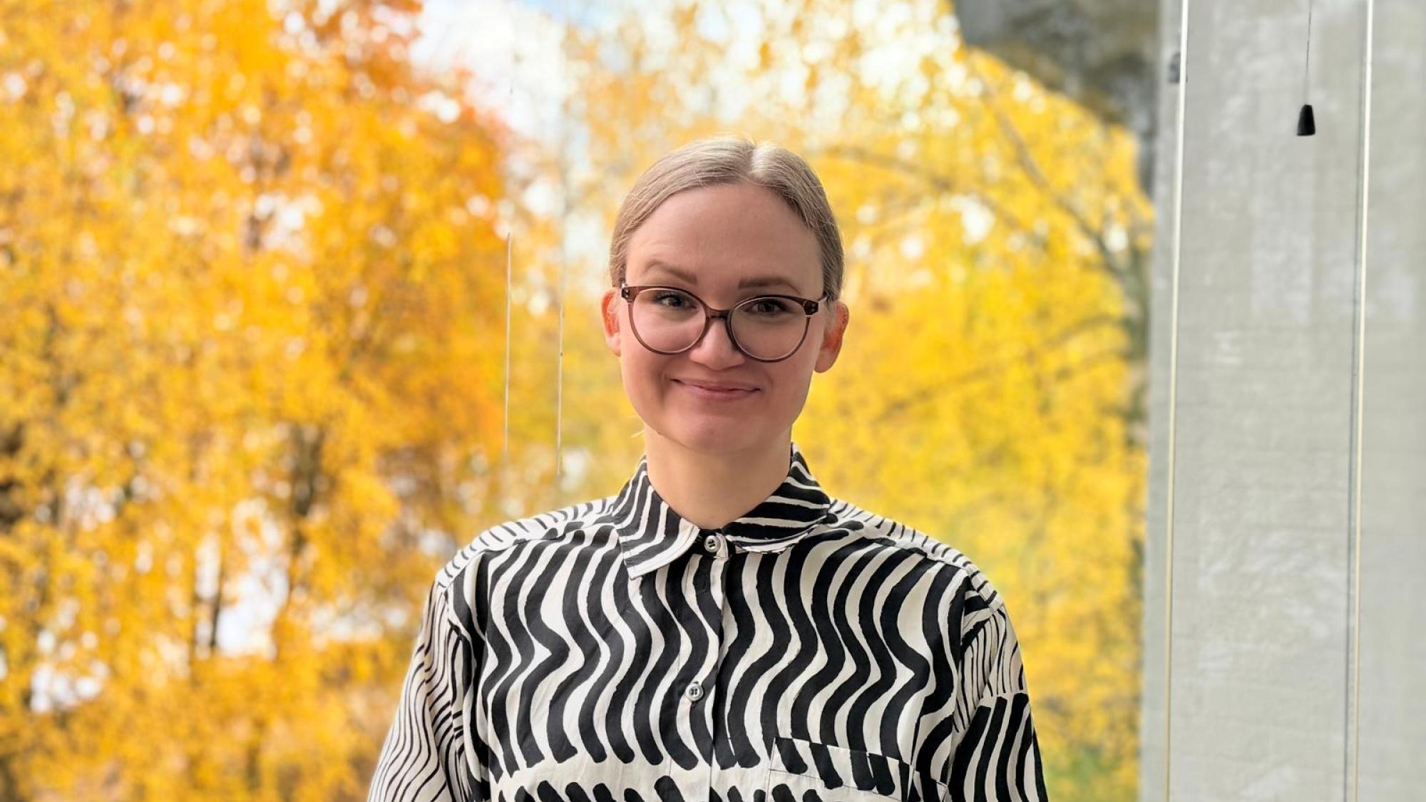 Merja Kivirinta in a portrait photo with yellow trees in the background